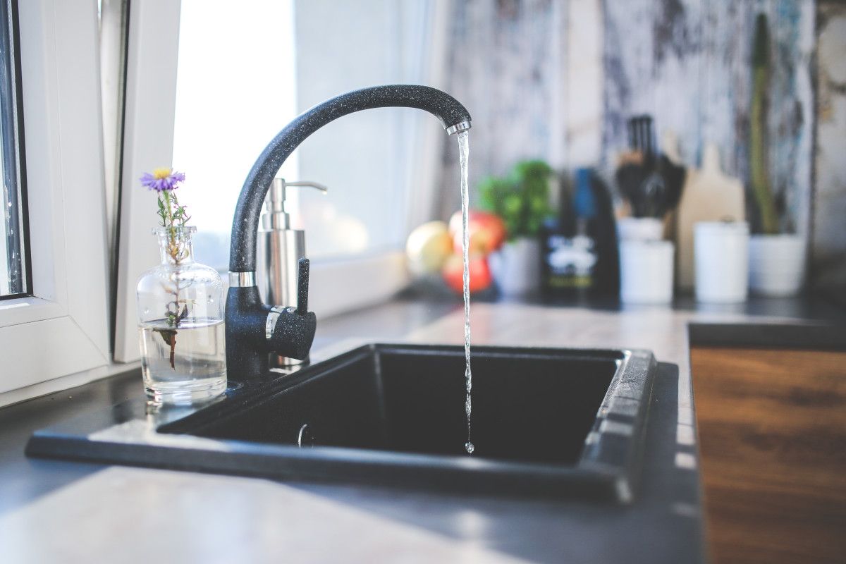 Close-up of brown rusty water flowing from a kitchen faucet